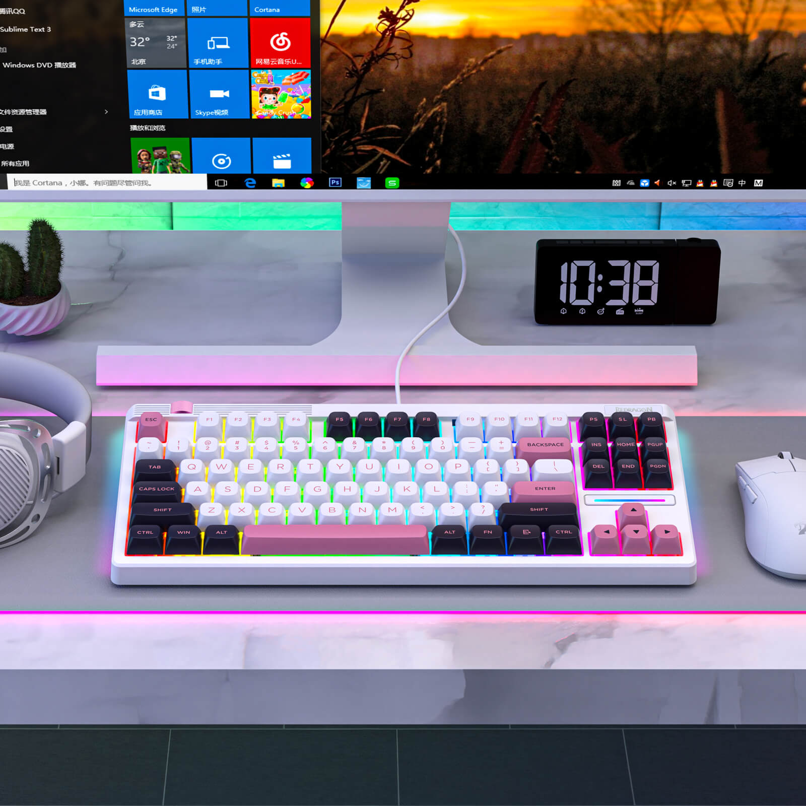 Keyboard on a desk with a computer monitor displaying a colorful interface, clock, and cactus plant.